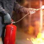 Man using fire extinguisher fighting fire closeup photo.